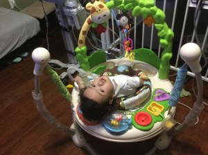 On the bouncer watching his nursery rhymes upside down!